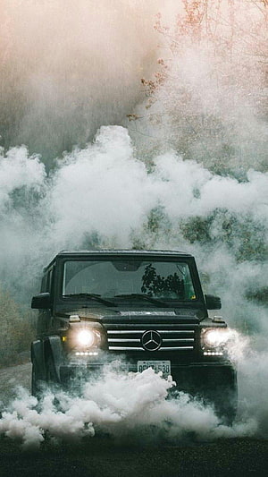 Black Mercedes-Benz G-Class SUV Driving Through Thick White Smoke in a Misty Forest HD phone wallpaper