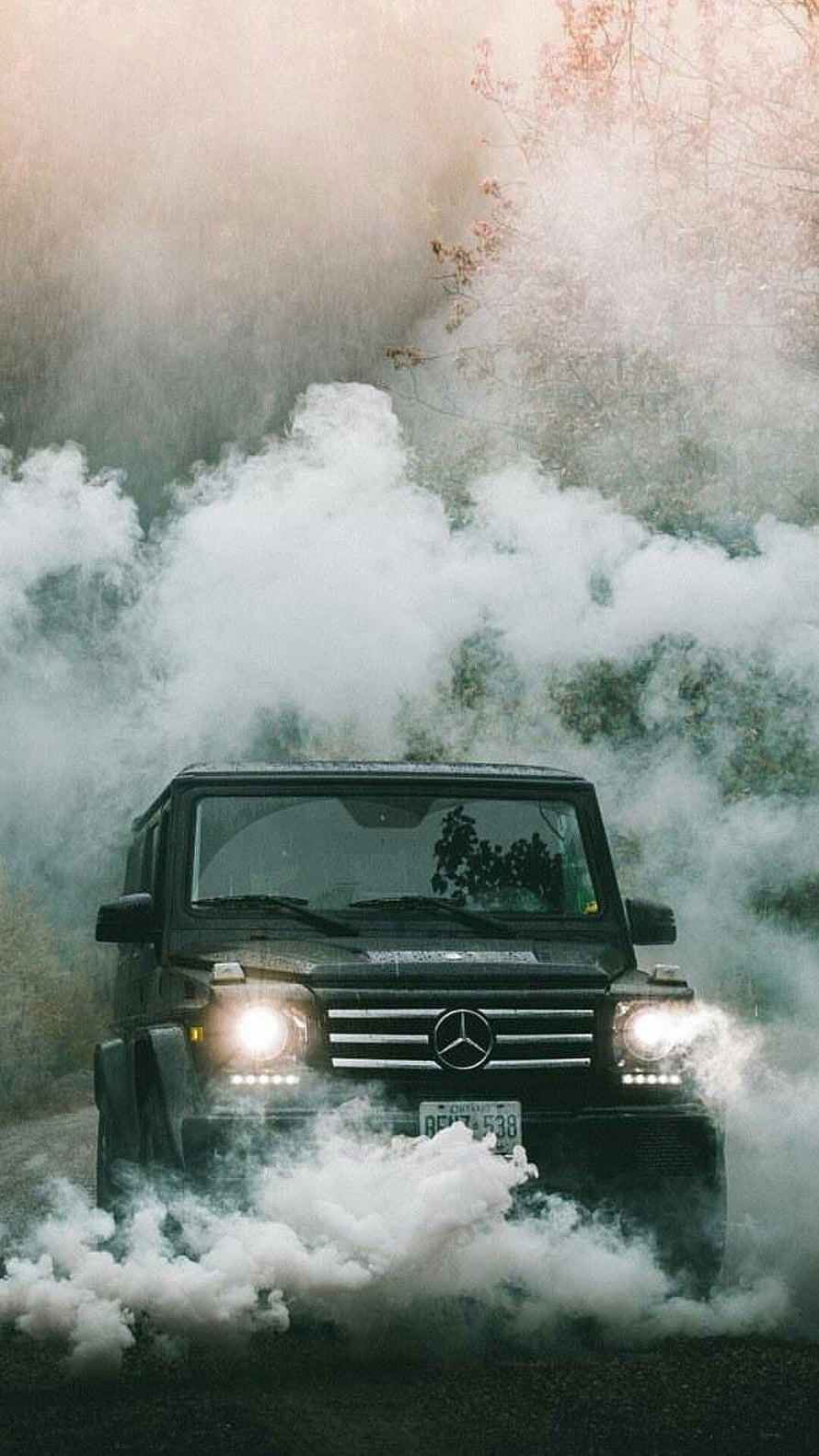 Black Mercedes-Benz G-Class SUV Driving Through Thick White Smoke in a Misty Forest HD phone wallpaper
