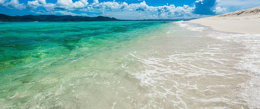 Turquoise Shallow Waters Lapping Against White Sand Beach Under a Bright Blue Sky HD wallpaper