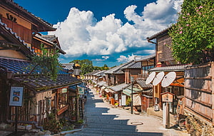 Traditional Kyoto Street Scene With Wooden Houses And Japanese Umbrellas Under A Bright Summer Sky HD wallpaper