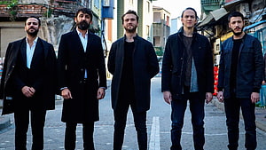 Five men in dark coats standing on a narrow urban street in Turkey HD wallpaper