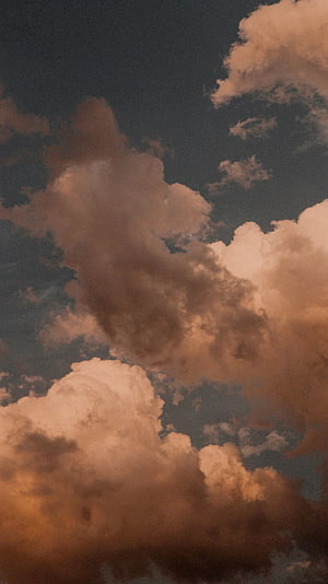 Dramatic Cumulus Clouds in Warm Sepia Tones Against a Dark Sky HD phone wallpaper
