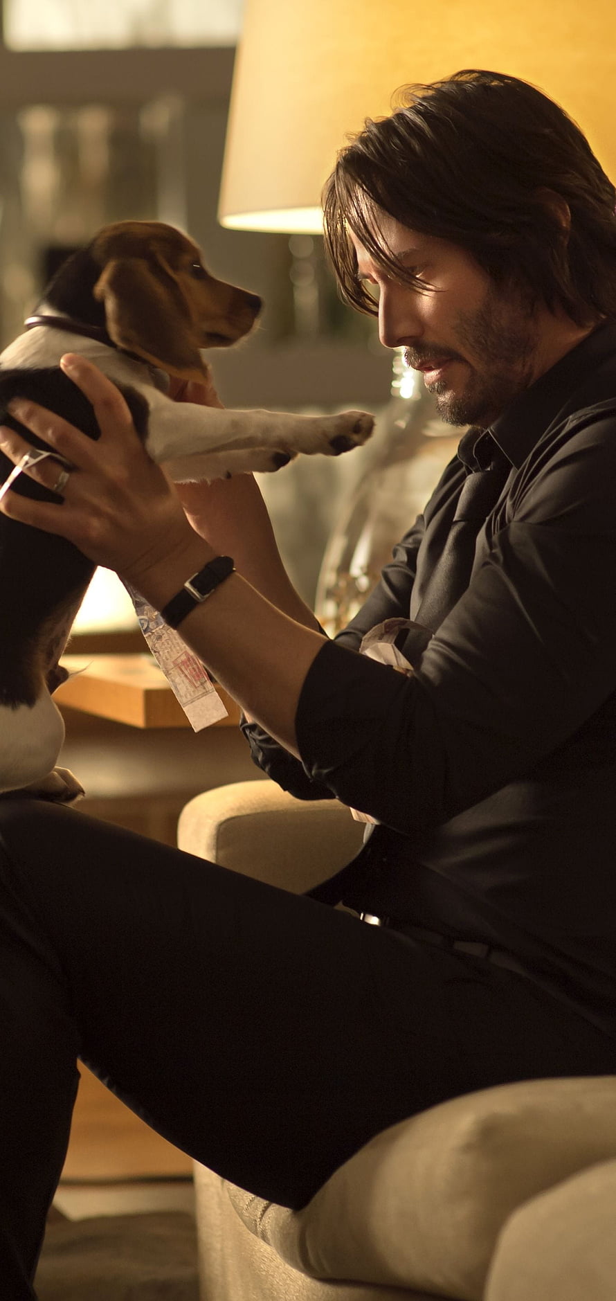 John Wick holding a beagle puppy in a warmly lit interior scene HD phone wallpaper