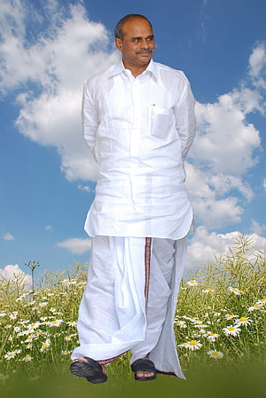 Dr. YSR in traditional white dhoti and shirt standing in a daisy field under a blue sky HD phone wallpaper