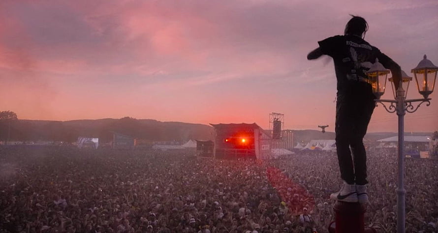Travis Scott performing at a massive outdoor music festival during a vibrant sunset HD wallpaper