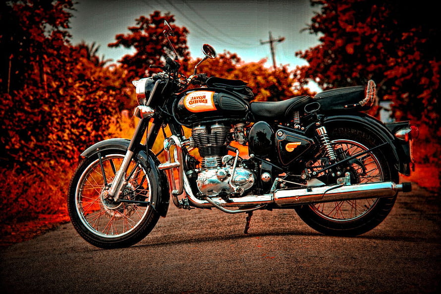 Classic Royal Enfield Bullet Motorcycle with Orange Tank on Rural Road HD wallpaper