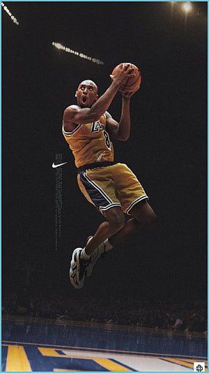 Kobe Bryant in mid-air dunk wearing Los Angeles Lakers jersey on a dark basketball court HD phone wallpaper