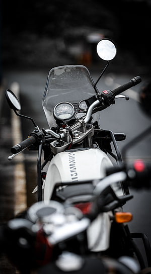 Close-up of a white Kawasaki motorcycle handlebars and dashboard with analog gauges and windscreen HD phone wallpaper