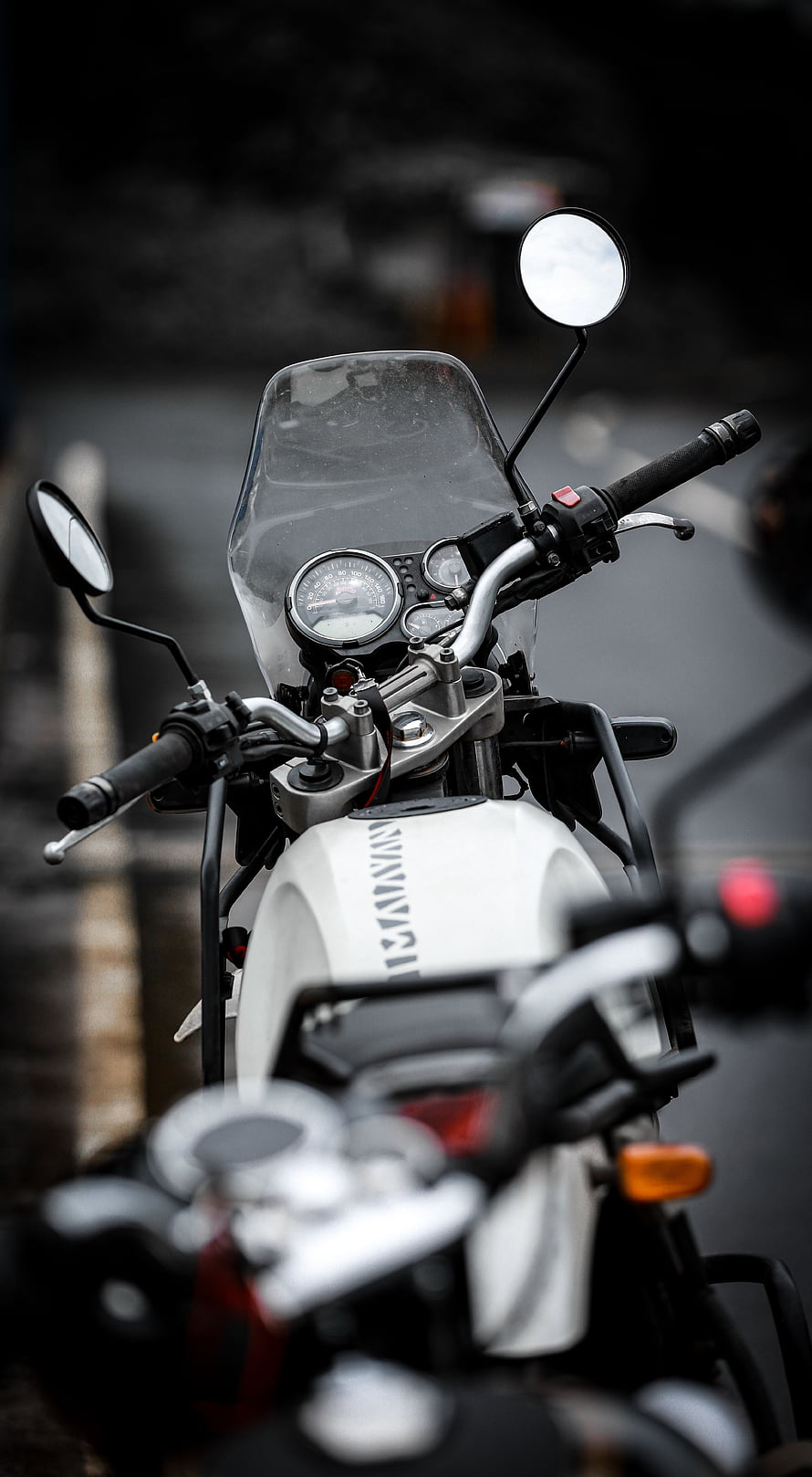Close-up of a white Kawasaki motorcycle handlebars and dashboard with analog gauges and windscreen HD phone wallpaper