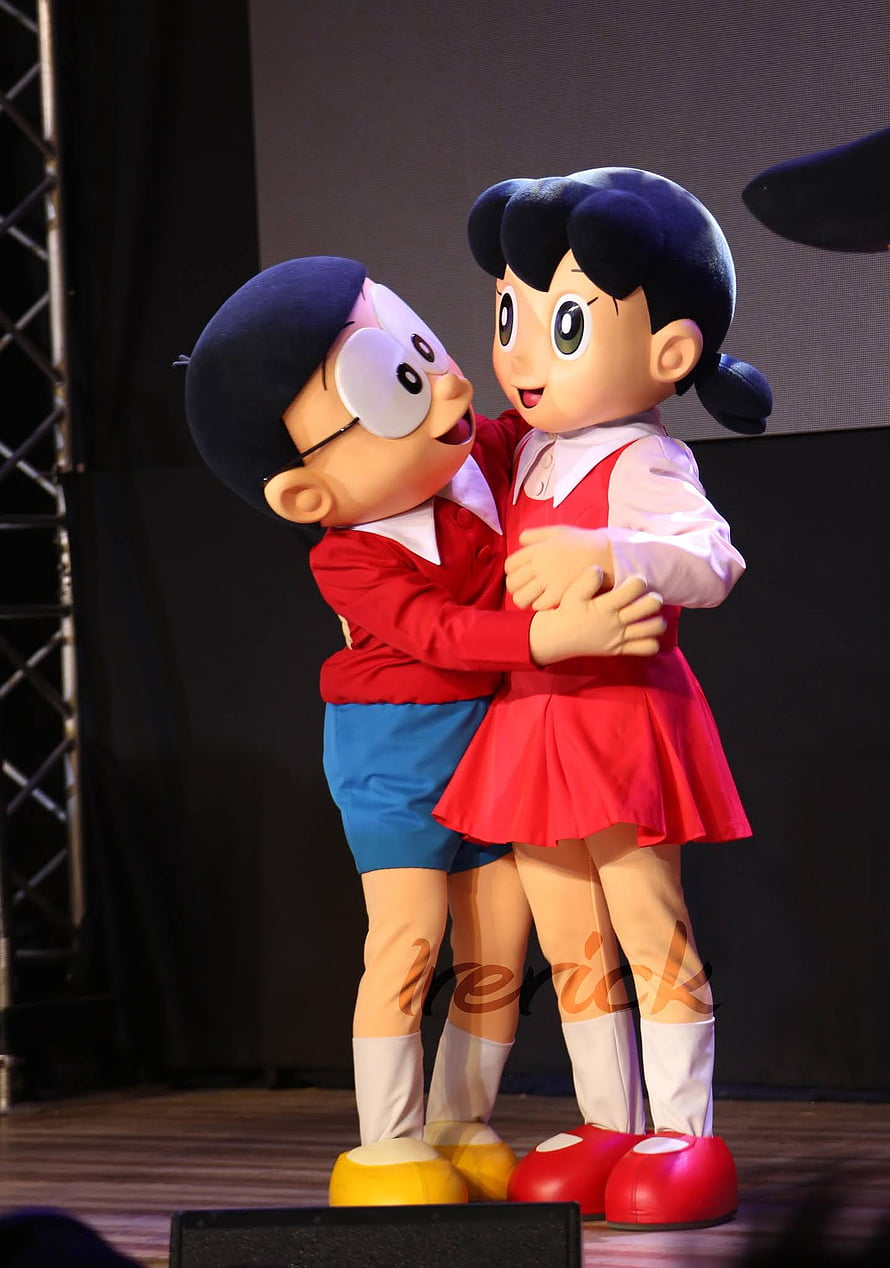 Nobita and Shizuka Doraemon Mascot Characters Hugging on Stage HD phone wallpaper