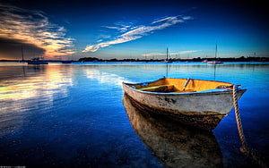 Weathered Wooden Rowboat Moored in Calm Harbor at Sunset with Sailboats in Distance HD wallpaper
