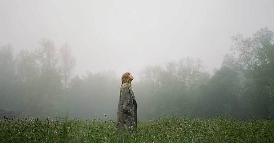 Woman in plaid coat standing in a foggy green field looking up at the misty sky, Pin on Folklore, taylor swift albums HD wallpaper