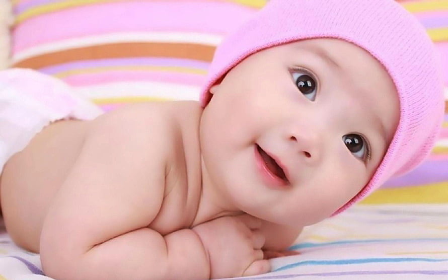 Smiling Baby Girl Wearing Pink Beanie Hat Lying on Striped Bedding HD wallpaper