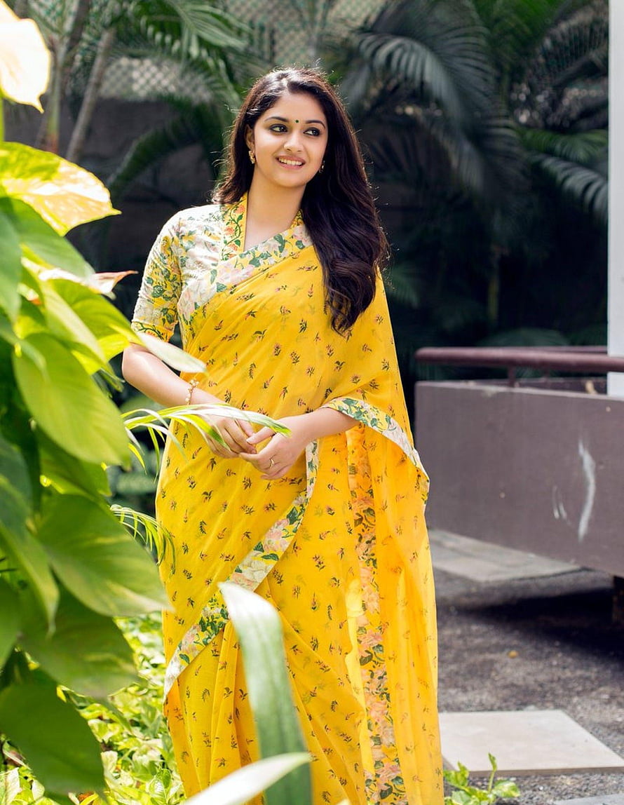 Keerthi Suresh in a Vibrant Yellow Floral Saree Amidst Lush Tropical Greenery HD phone wallpaper