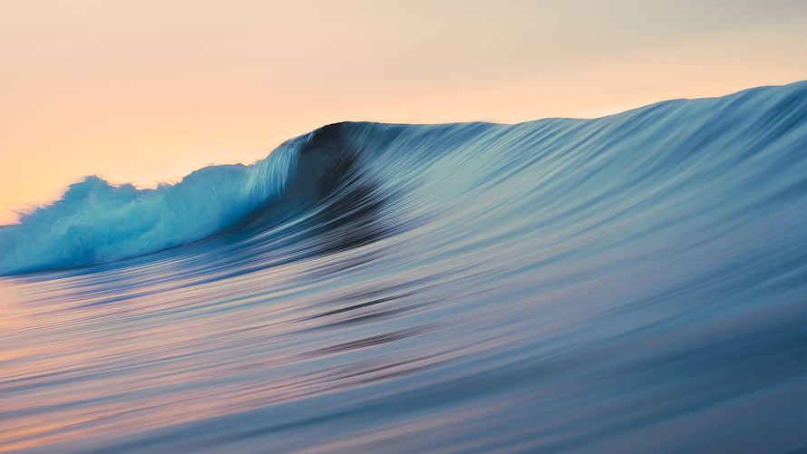 Majestic Ocean Wave Curling at Sunset with Soft Pastel Sky and Turquoise Water HD wallpaper