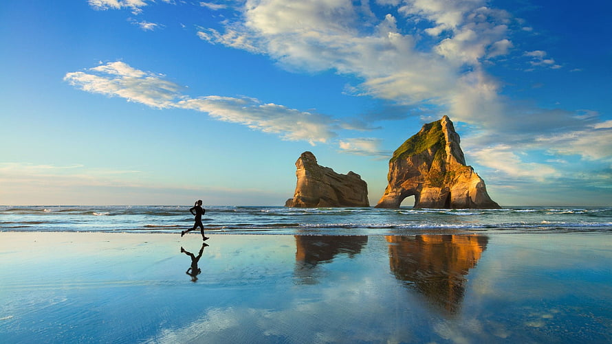 Runner Silhouette on Wet Sand with Coastal Sea Stacks and Mirror Reflections HD wallpaper