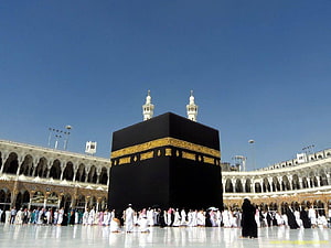 The Sacred Kaaba in Mecca with Pilgrims Performing Tawaf Under a Clear Blue Sky HD wallpaper