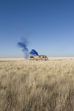 RV in a dry grassy field with blue smoke rising into a clear blue sky HD phone wallpaper