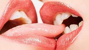 Close-up of two people sharing an intimate kiss with glossy red lips and visible teeth HD wallpaper
