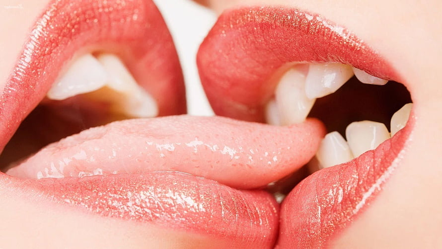Close-up of two people sharing an intimate kiss with glossy red lips and visible teeth HD wallpaper