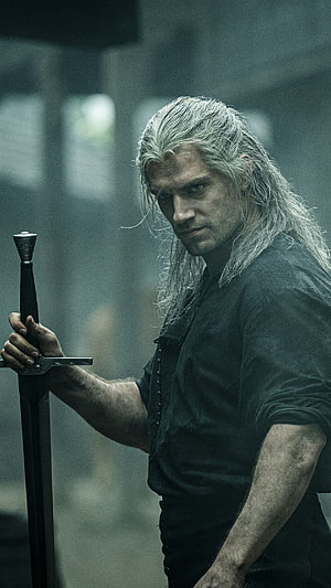Geralt of Rivia from The Witcher holding a sword in a dark, moody setting HD phone wallpaper
