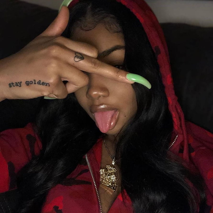 Young woman in red hoodie with long green nails and hand tattoo making a playful face, 75 about baddies⚡, hood baddie pfp HD phone wallpaper