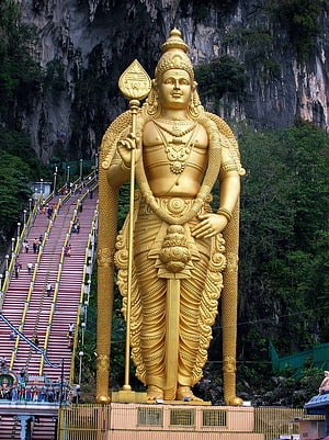 Golden Murugan Statue at Batu Caves with Staircase and Limestone Cliff HD phone wallpaper