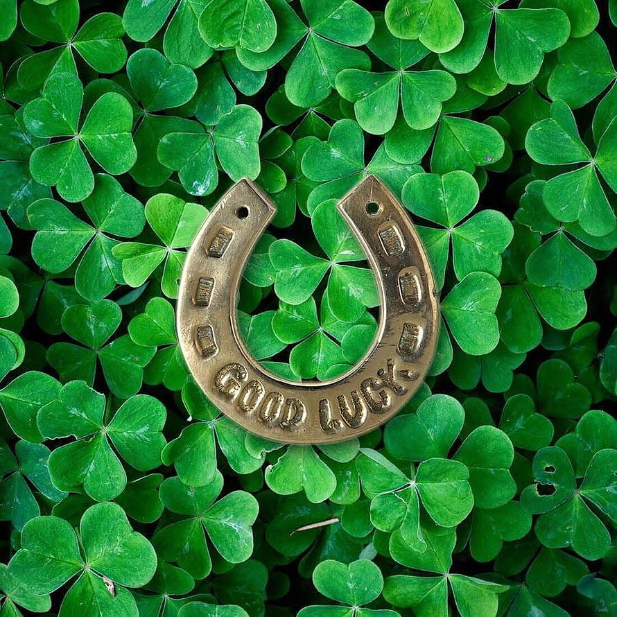 Vintage Brass Good Luck Horseshoe Resting on a Bed of Vibrant Green Clover Leaves HD phone wallpaper