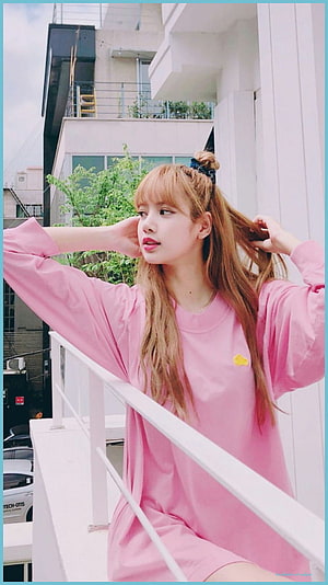 Lisa from BLACKPINK in a pink oversized dress on a white balcony with urban buildings in the background HD phone wallpaper