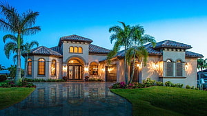 Florida Luxury Mediterranean Mansion at Dusk with Palm Trees and Wet Driveway HD wallpaper