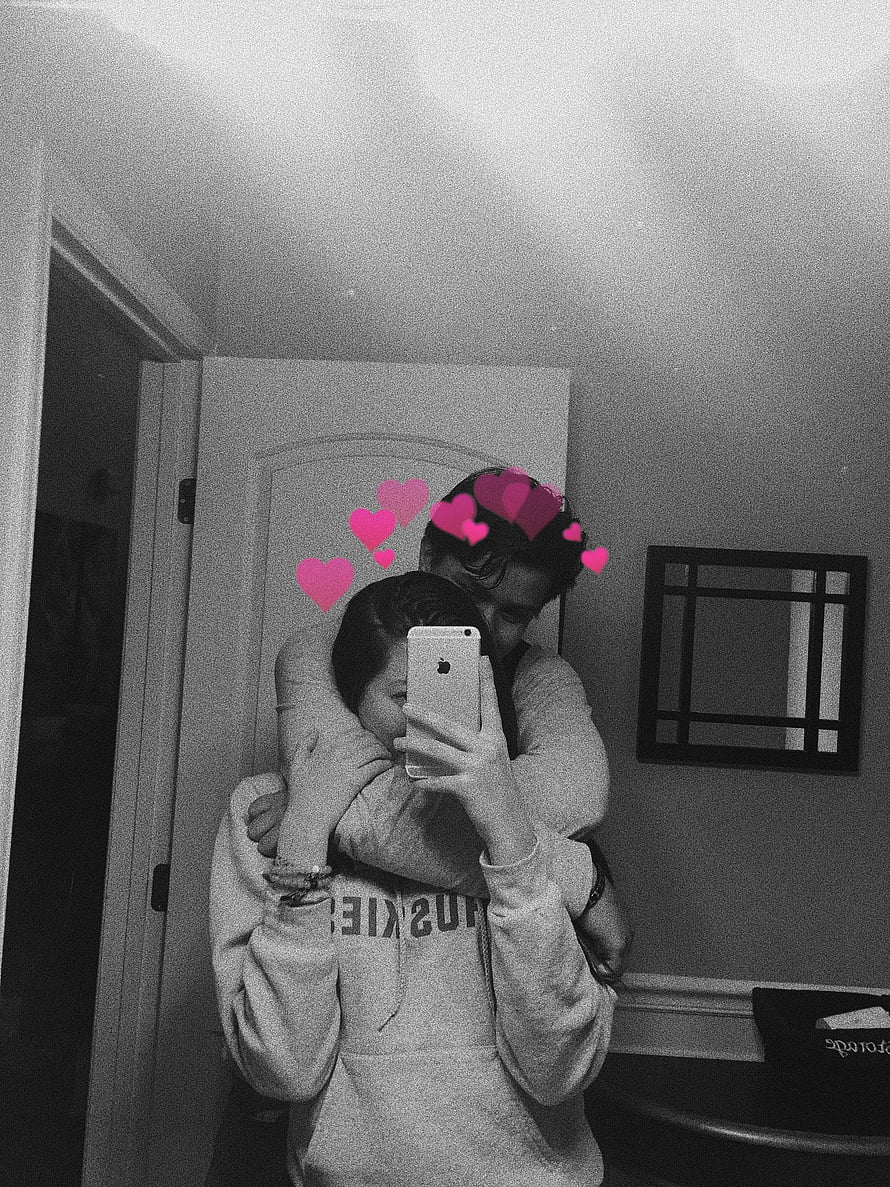 Black and white mirror selfie of a couple embracing with pink heart stickers HD phone wallpaper