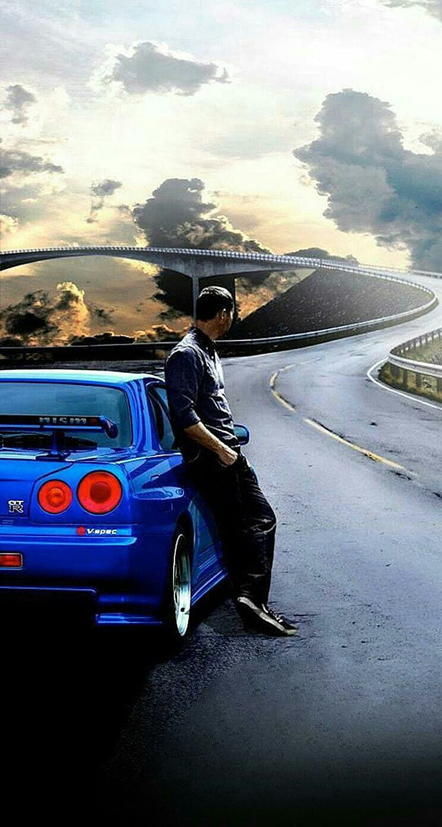 Paul Walker Leaning Against Blue Nissan Skyline GT-R on Winding Mountain Road at Sunset HD phone wallpaper