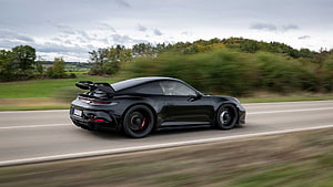 Black Porsche 911 GT3 RS speeding on a country road with motion blur HD wallpaper