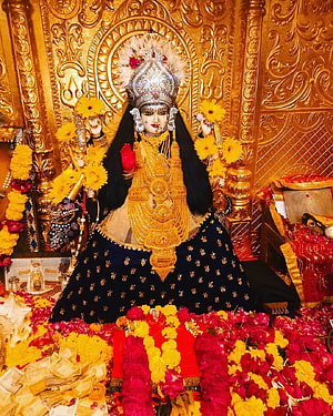 Ornate Hindu Goddess Idol Adorned in Gold Jewelry and Marigold Garlands HD phone wallpaper