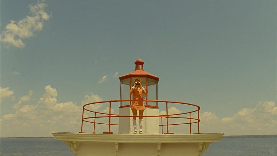 Wes Anderson film still of a woman in an orange dress standing on a lighthouse platform at sea, wes anderson movies, #wes anderson HD wallpaper