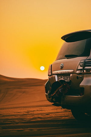 Toyota Land Cruiser parked in golden desert dunes at sunset HD phone wallpaper