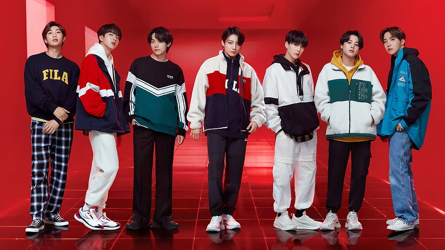 BTS members wearing FILA sportswear in a vibrant red studio setting HD wallpaper