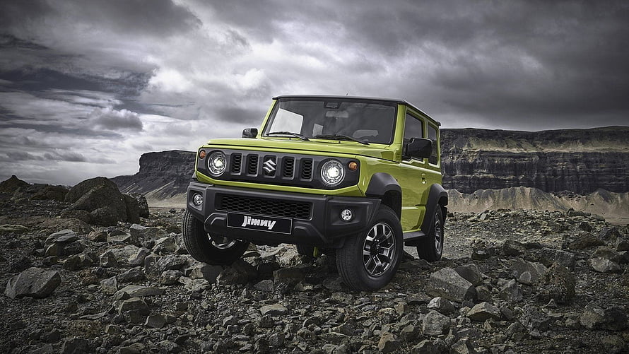 Lime Green Suzuki Jimny Off-Road SUV on Rocky Terrain Under Dramatic Stormy Sky HD wallpaper