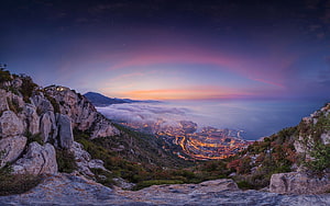 Coastal City at Dusk with Sea of Clouds and Rocky Mountain Foreground HD wallpaper