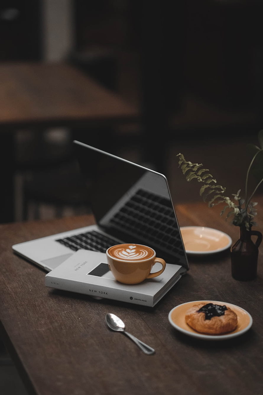 Cozy Cafe Workspace With Laptop, Latte Art, and Pastry on Wooden Table HD phone wallpaper