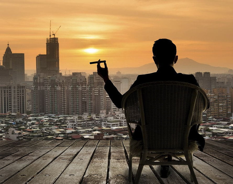 Silhouette of a man in a suit smoking a cigar on a rooftop overlooking a city skyline at sunset, Billionaire Luxury Lifestyle posted by Ryan Walker, billionaire lifestyle HD wallpaper