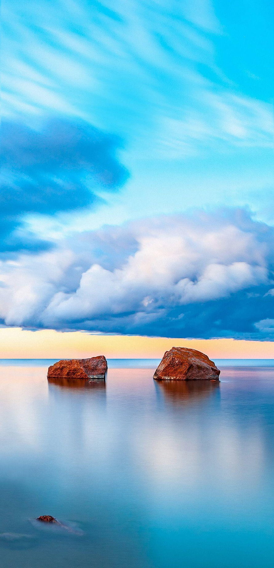 Serenity of Two Red Rocks in Calm Ocean Waters Under a Dramatic Cloudy Sky HD phone wallpaper