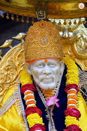 Close-up of a white marble statue of a Hindu deity adorned with a golden crown and flower garlands HD phone wallpaper