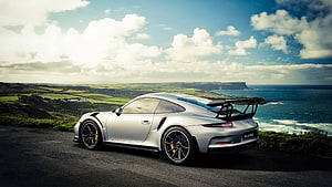 Silver Porsche 911 GT3 RS parked on a coastal cliff overlooking the ocean HD wallpaper