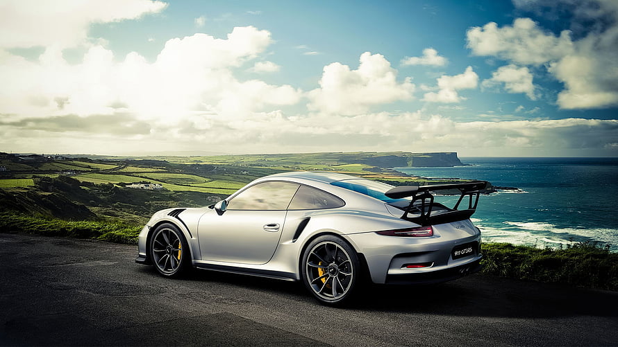 Silver Porsche 911 GT3 RS parked on a coastal cliff overlooking the ocean HD wallpaper