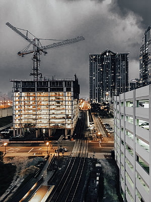 Urban Construction Site at Dusk with Tower Crane and Elevated Rail Tracks HD phone wallpaper