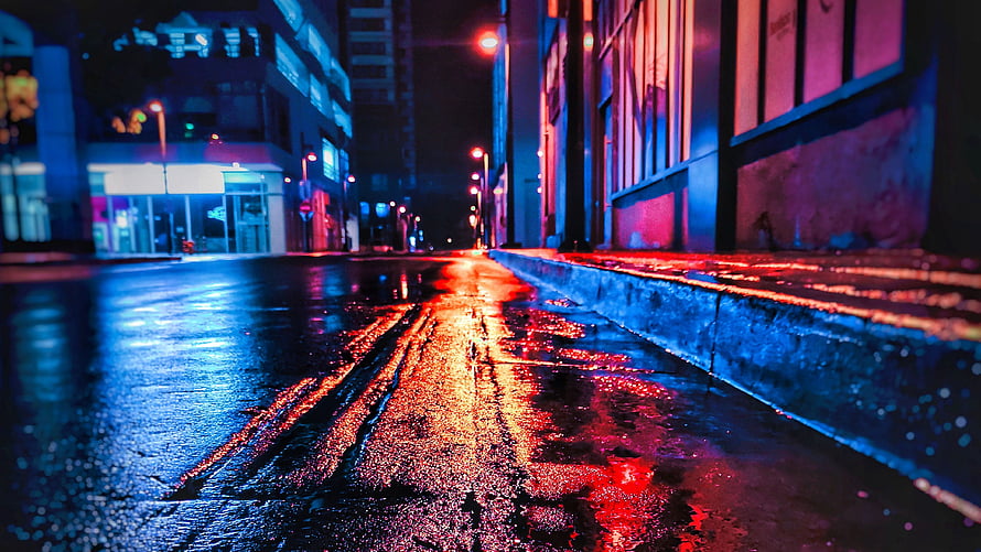 Neon-lit wet city street at night with vivid red and blue reflections on rain-soaked asphalt HD wallpaper