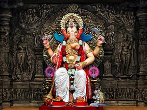 Ornate Ganesha Murti Seated on Temple Pedestal with Intricate Carved Stone Backdrop HD wallpaper