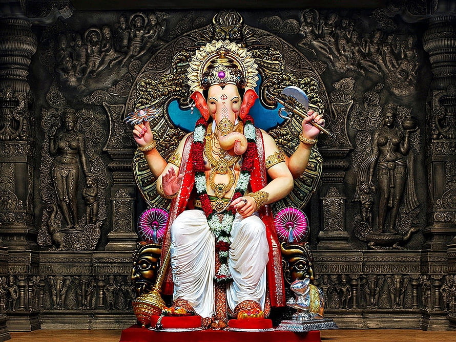 Ornate Ganesha Murti Seated on Temple Pedestal with Intricate Carved Stone Backdrop HD wallpaper