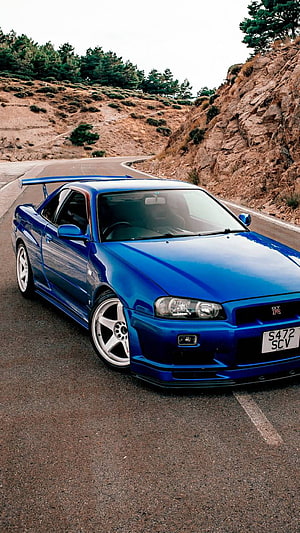 Blue Nissan Skyline R34 GT-R on a Winding Mountain Road HD phone wallpaper